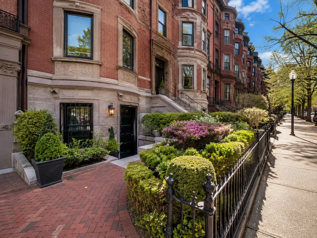 Brick building with manicured hedges and a sidewalk.